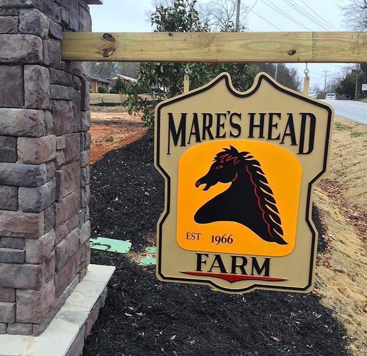 A mare 's head farm sign with a horse on it