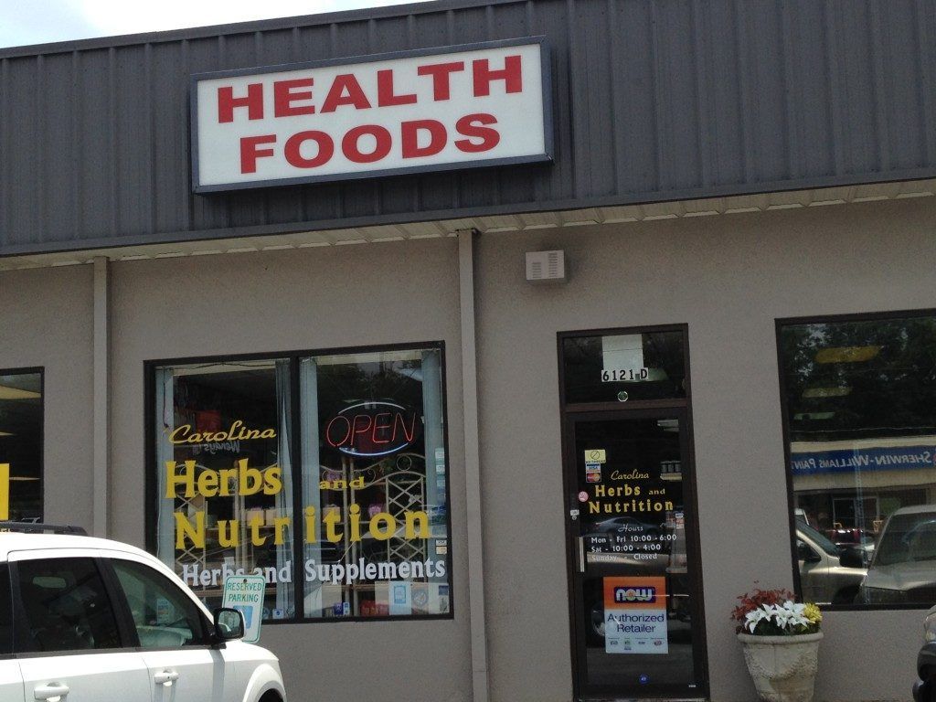 A white car is parked in front of a health foods store