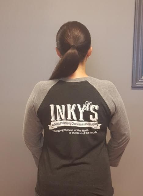 A woman is wearing a shirt that says inky 's on the back