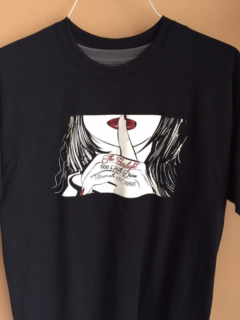 A black t-shirt with a picture of a woman holding her finger to her mouth