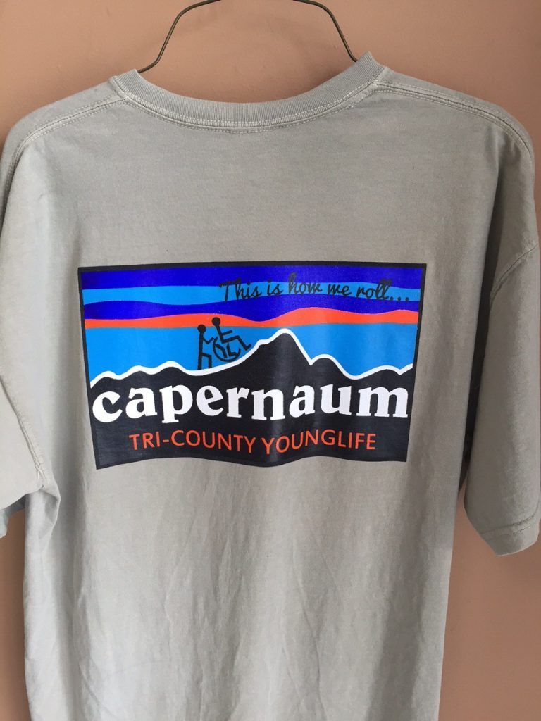 A grey capernaum tri-county younglife t-shirt hangs on a hanger