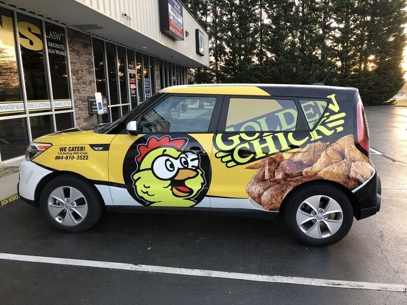 A car with a chicken on the side is parked in front of a building.