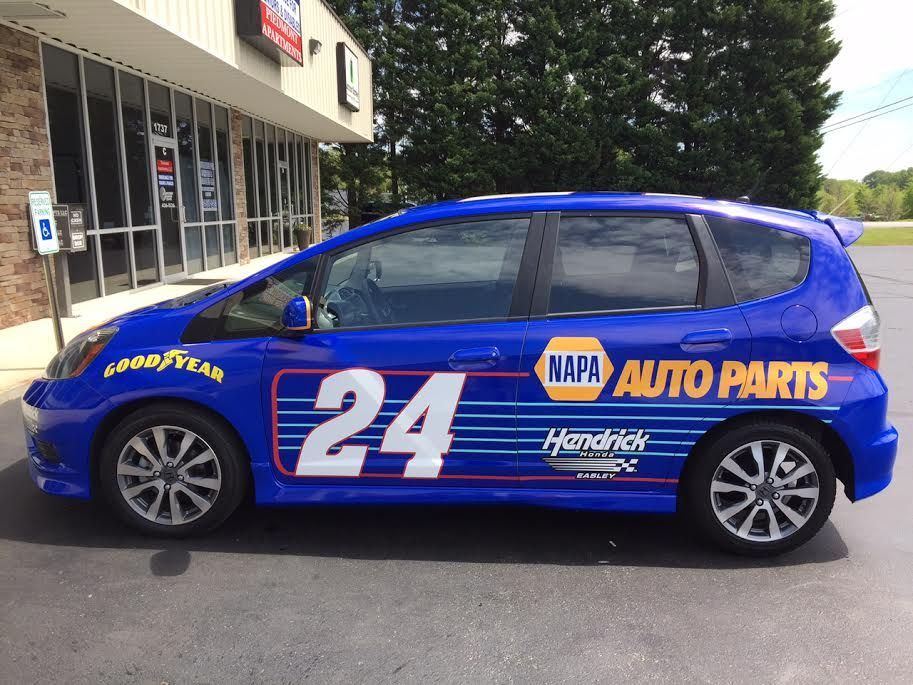 A blue napa auto parts car is parked in front of a building