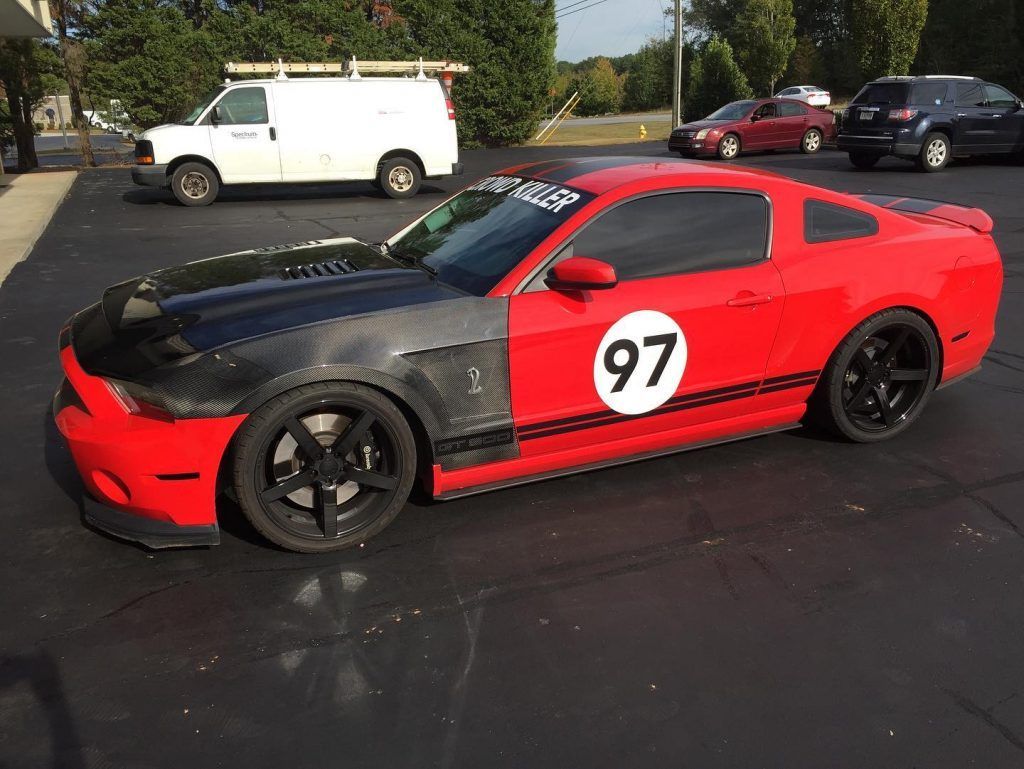 A red mustang with the number 97 on the side is parked in a parking lot.