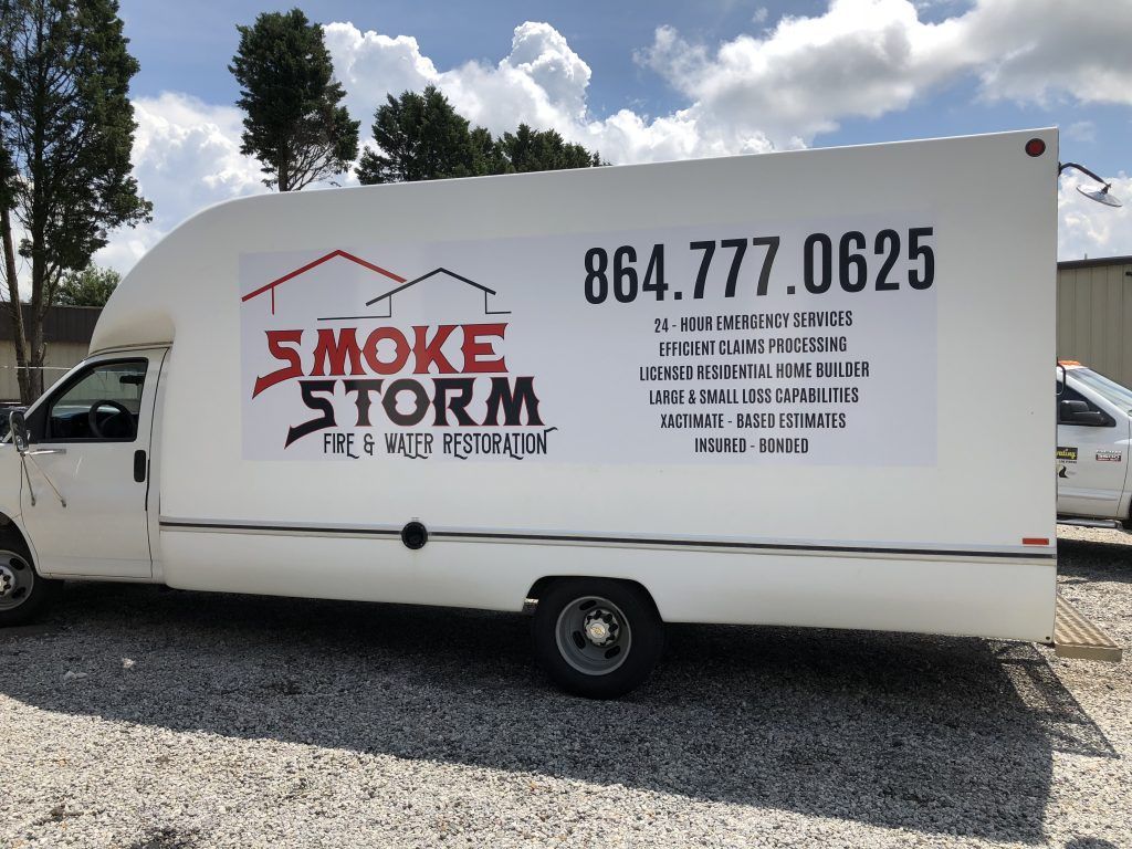 A white smoke storm truck is parked in a gravel lot.