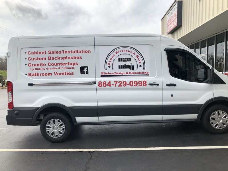 A white van is parked in a parking lot in front of a building.