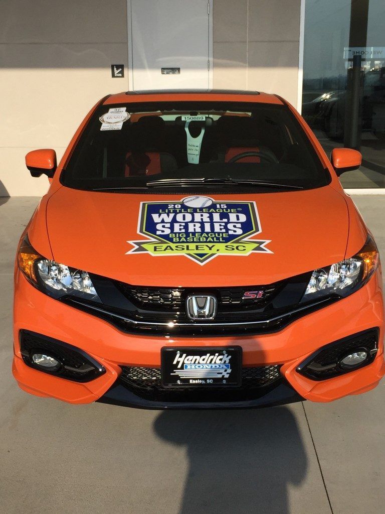 An orange honda civic is parked in front of a building.