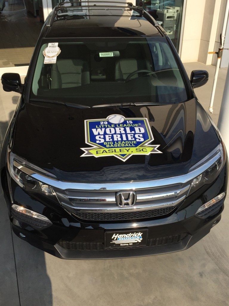 A black honda pilot is parked in front of a building.