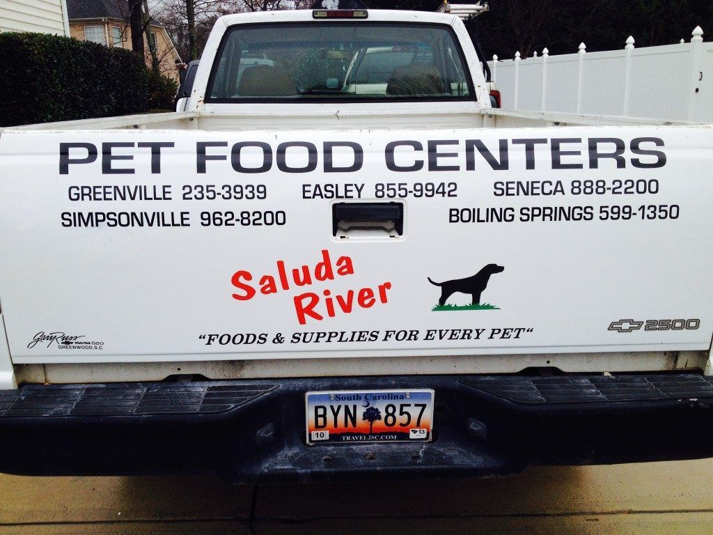 A white truck has a sign on the back that says pet food centers