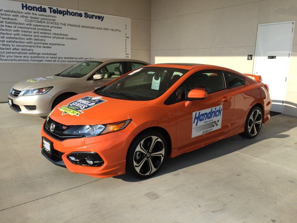 An orange honda civic is parked in a parking lot