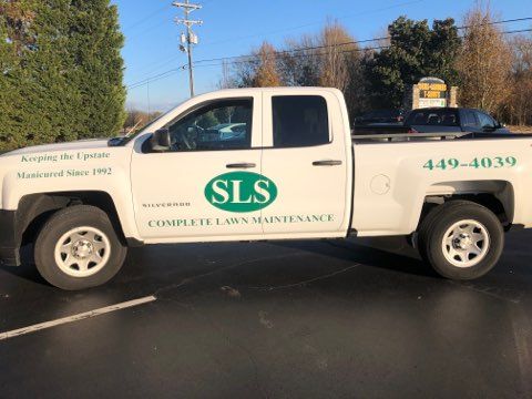 A white truck with the word sls on the side is parked in a parking lot.