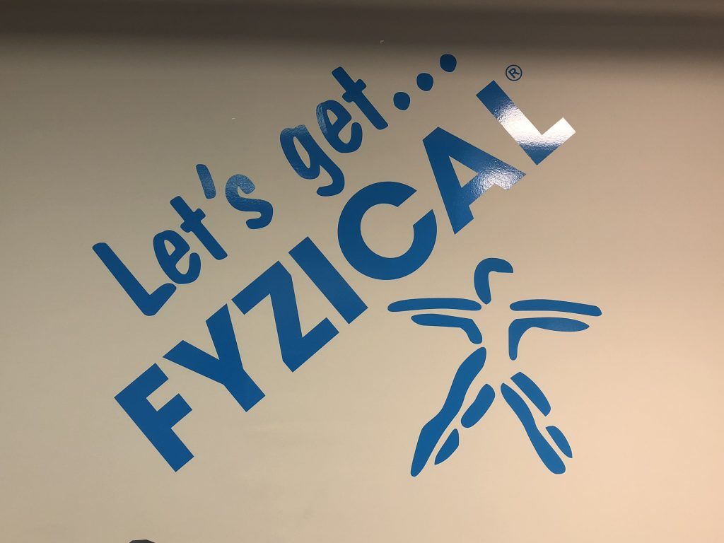A sign on a wall that says let 's get fyzical