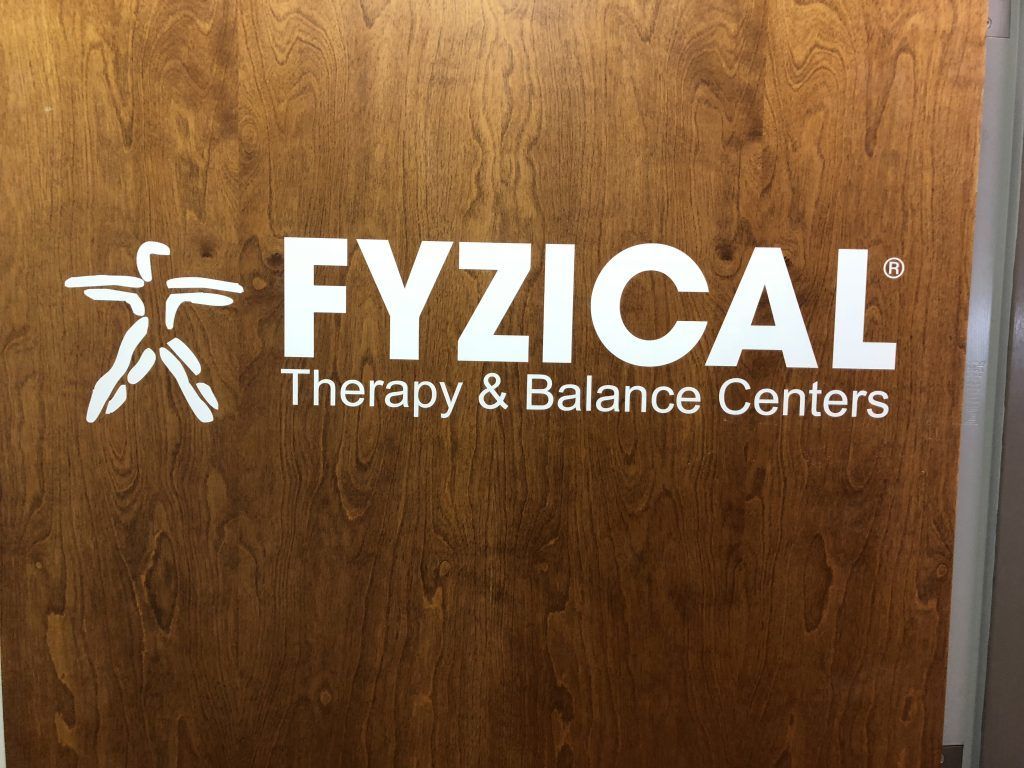 The logo for fyzical therapy and balance centers is on a wooden door.