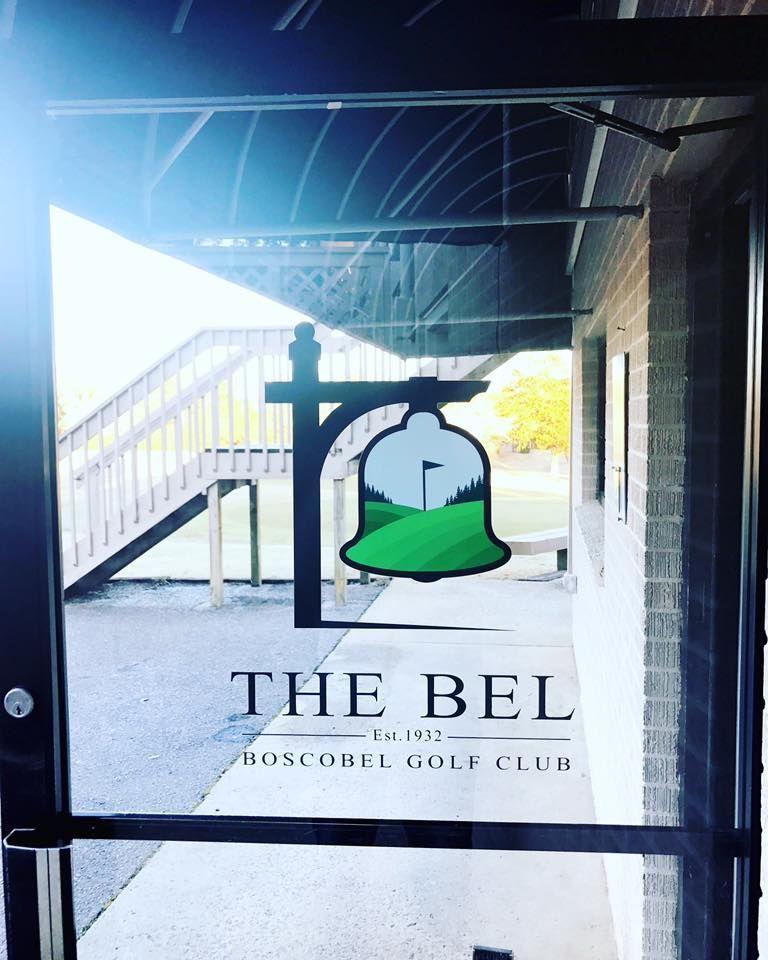 A sign for the bel golf club hangs on a glass door