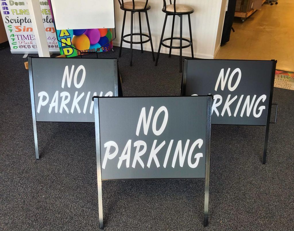 Three no parking signs are sitting on a carpeted floor