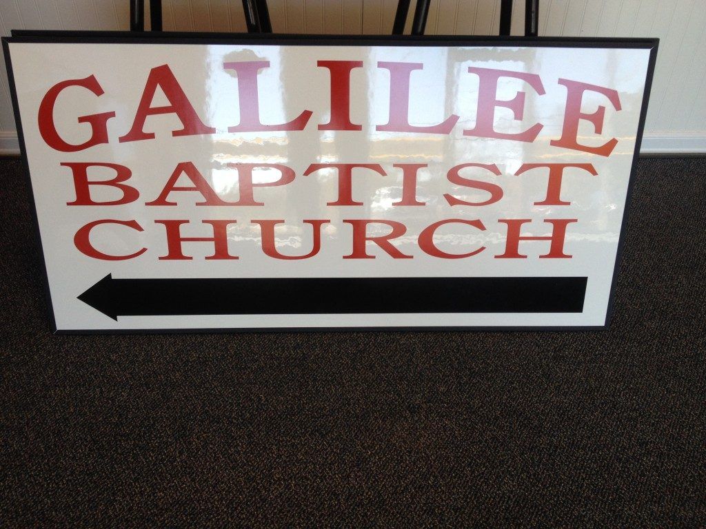 A sign for galilee baptist church with an arrow pointing to the right