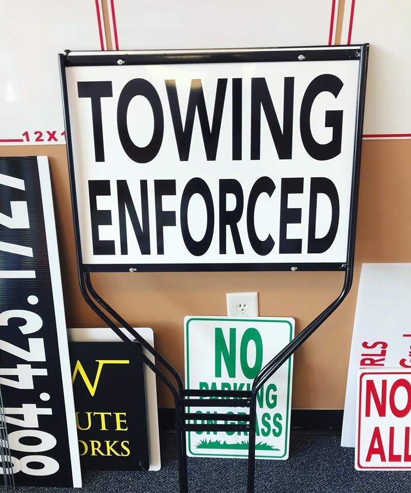 A towing enforced sign is surrounded by other signs