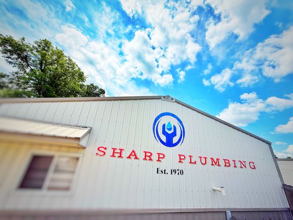 A white van for Sharp Plumbing is parked on the side of the road.