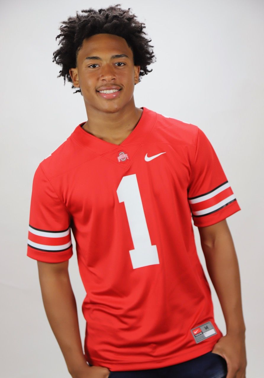 A young man wearing a red nike jersey with the number 1 on it