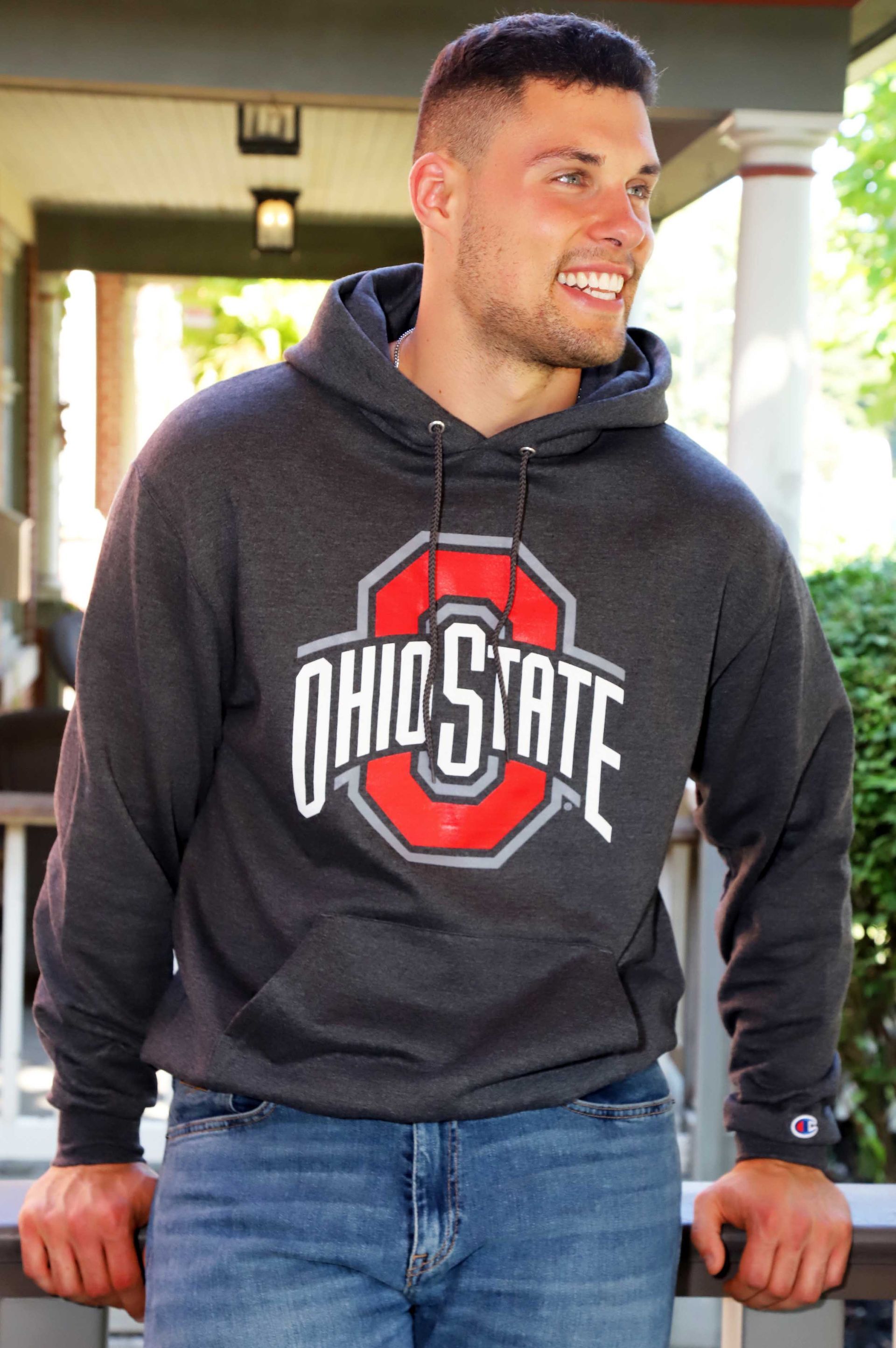 A man wearing a ohio state hoodie is leaning on a railing.