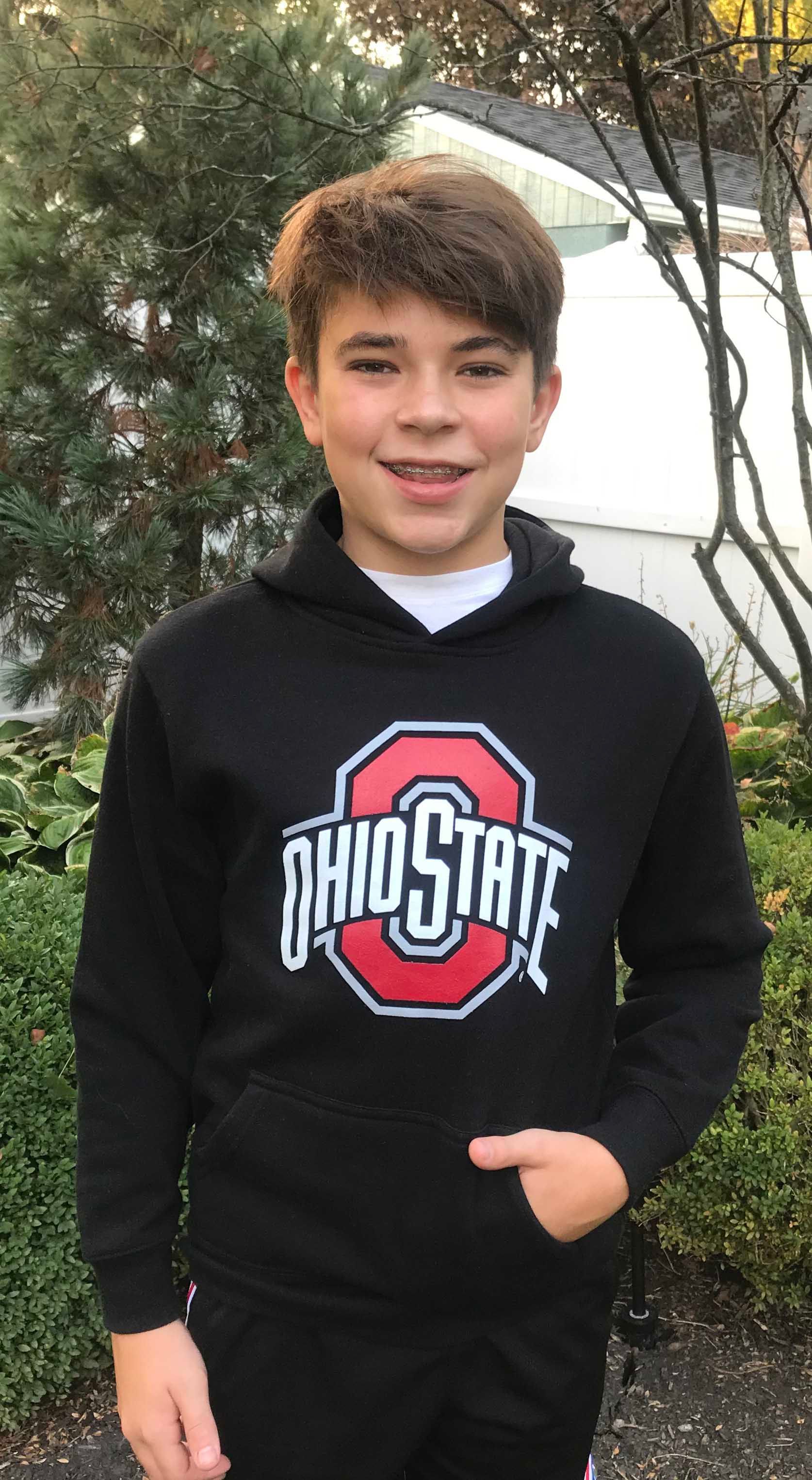 A young boy is wearing a black ohio state hoodie.