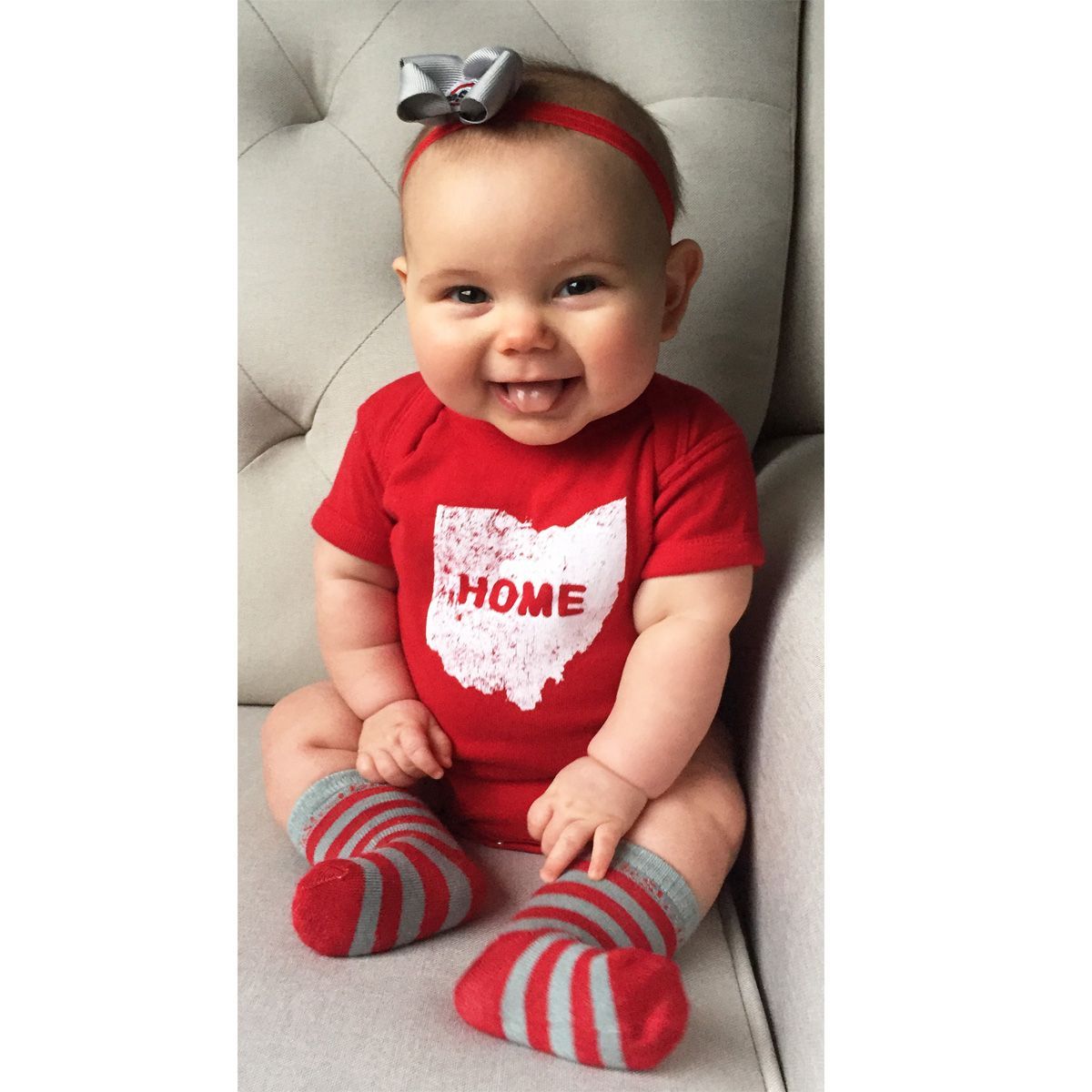 A baby wearing a red shirt that says home