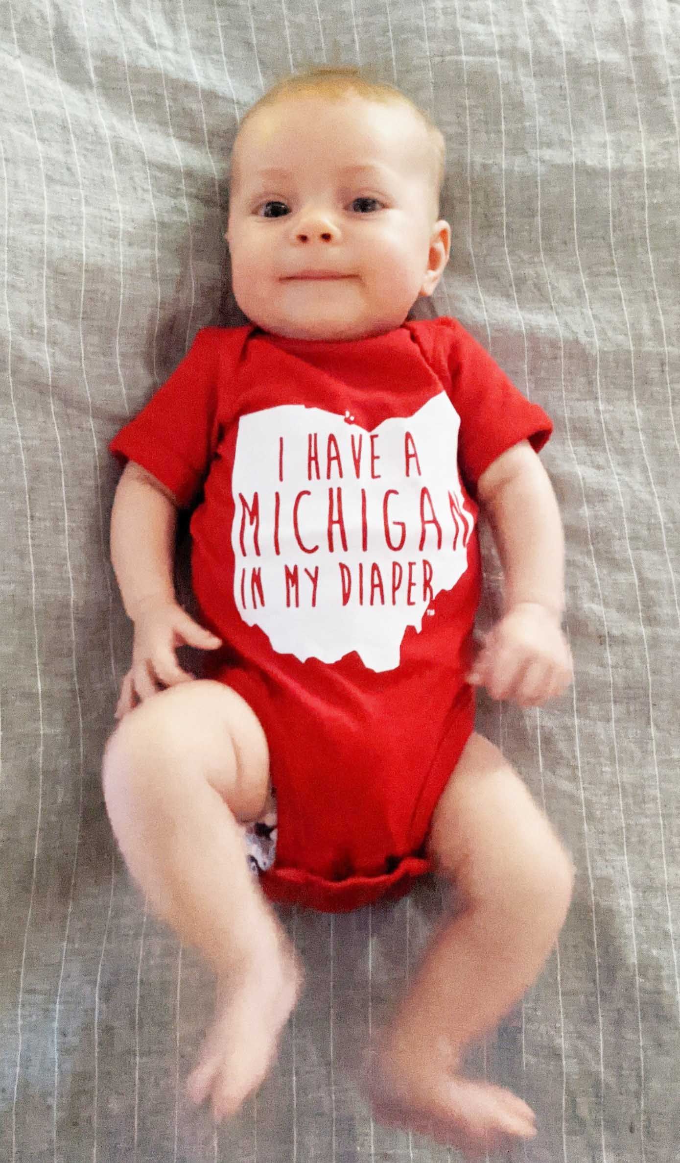 A baby wearing a red shirt that says i have a michigan in my diaper
