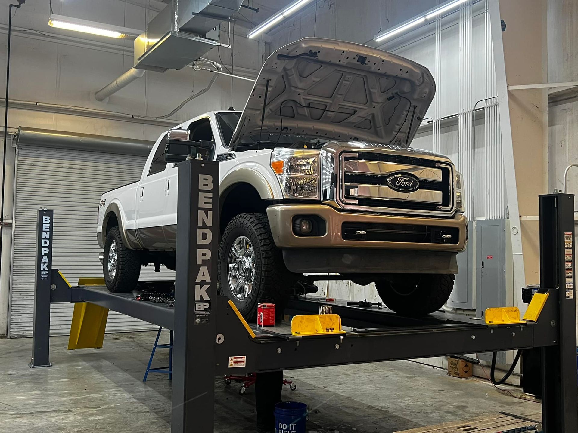 A ford truck is sitting on a lift in a garage.