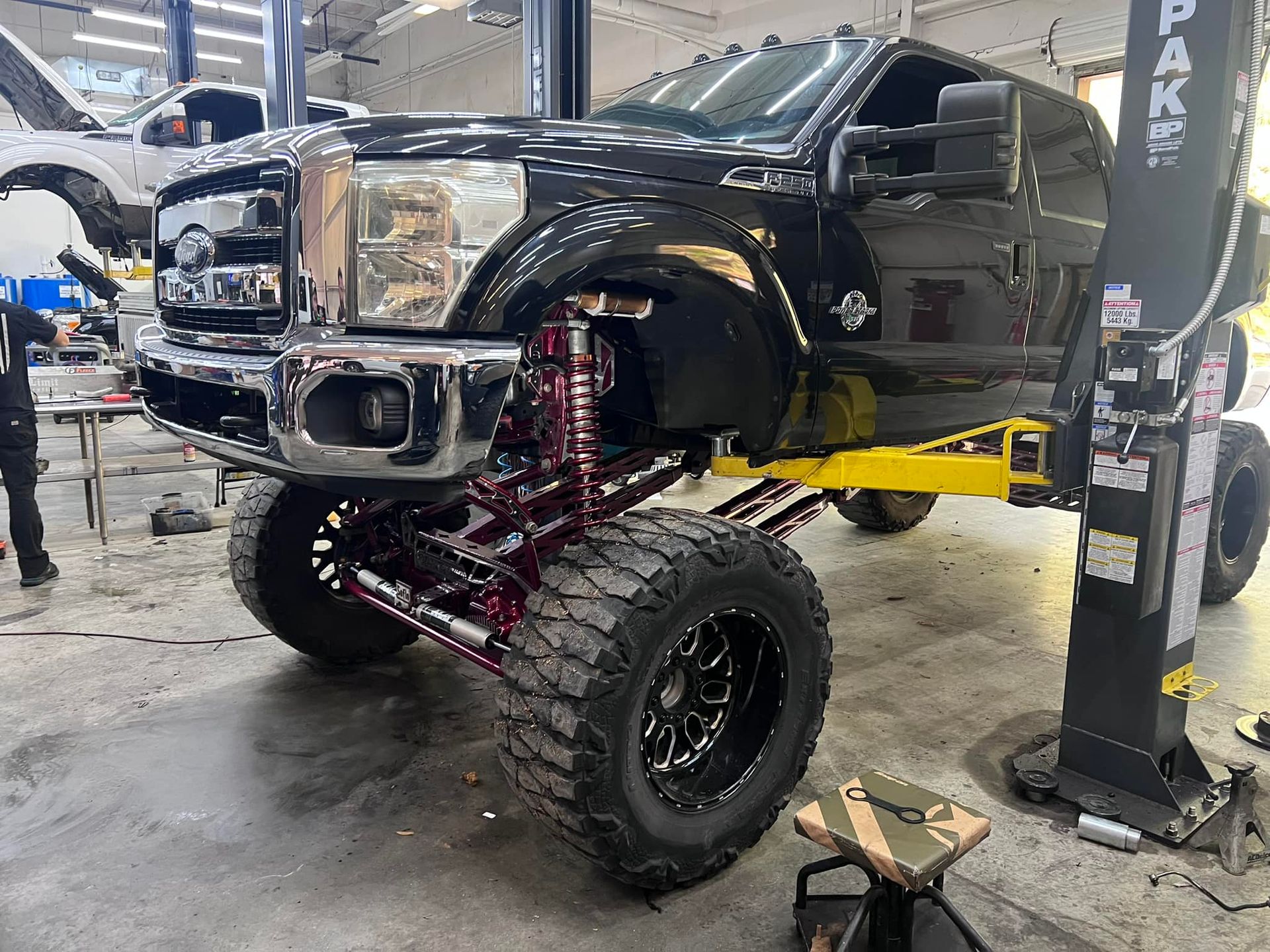 A black truck is sitting on a lift in a garage.