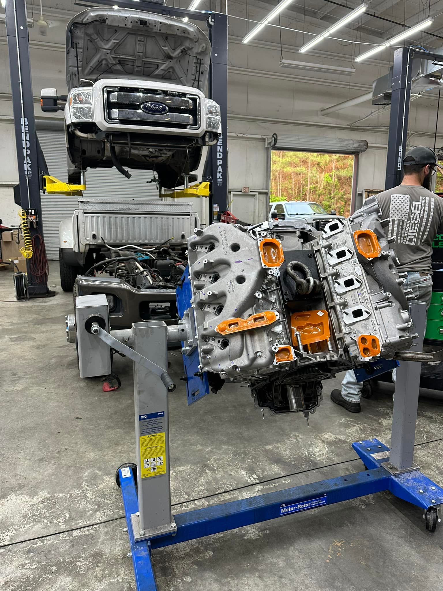 A man is working on a truck engine in a garage.