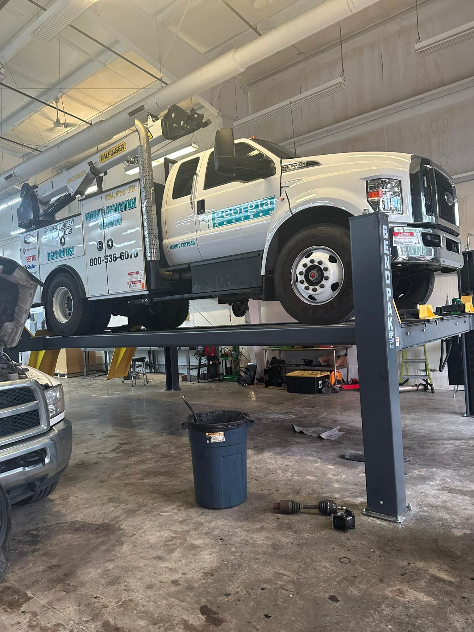 A white truck is sitting on a lift in a garage.