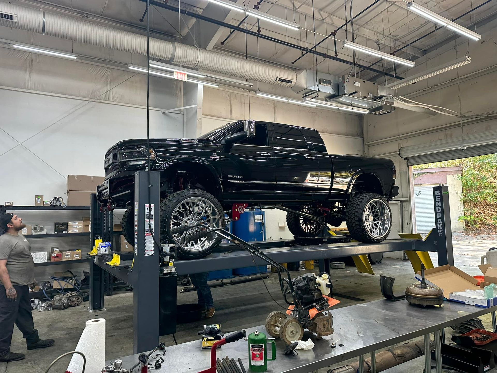 A black truck is sitting on a lift in a garage.