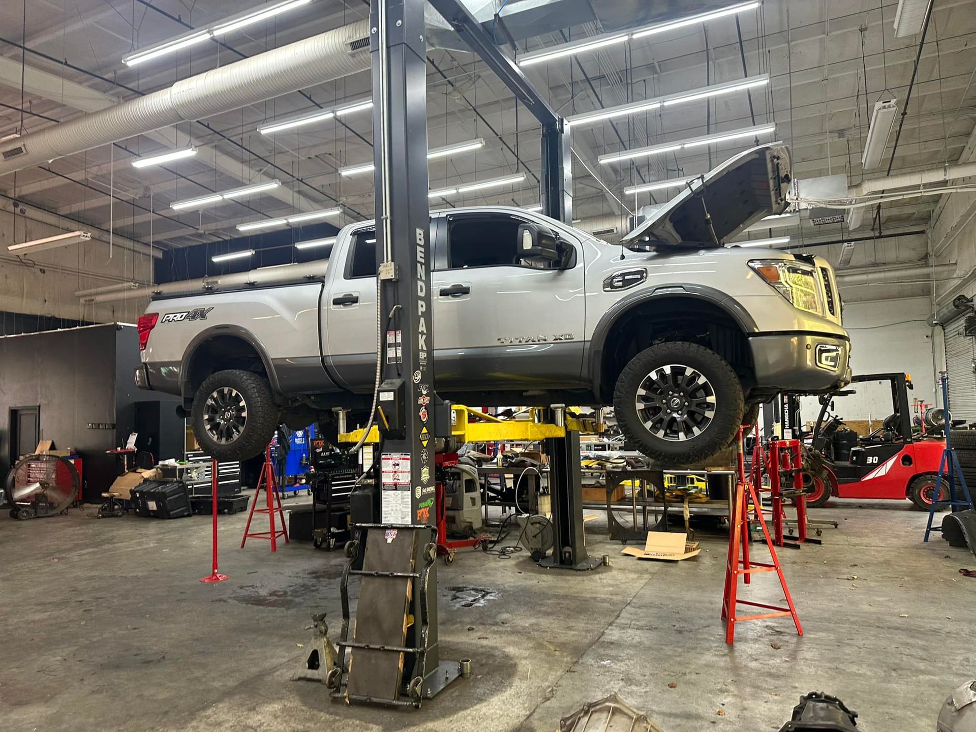 A truck is sitting on a lift in a garage.