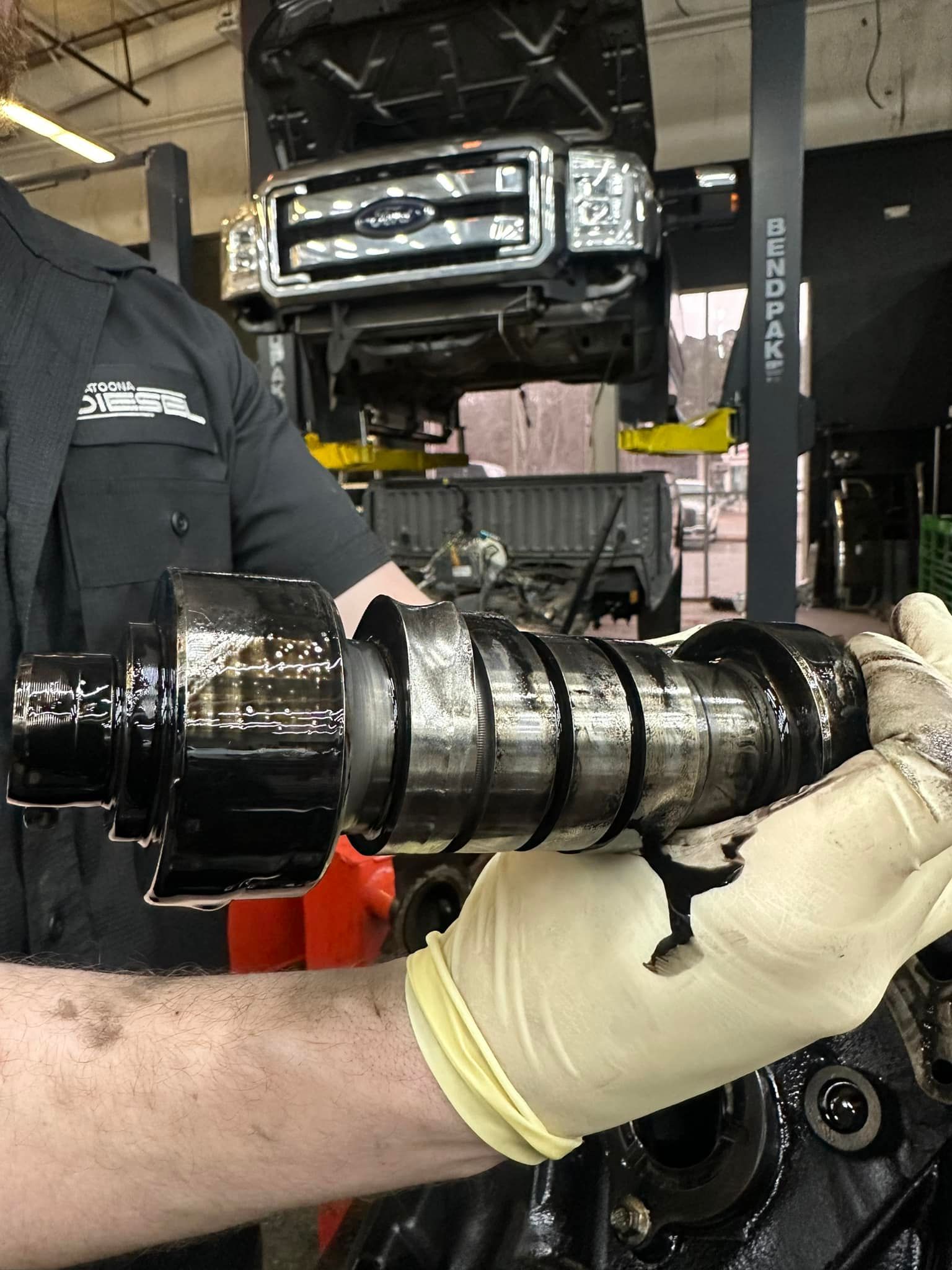 A man wearing gloves is working on a truck engine