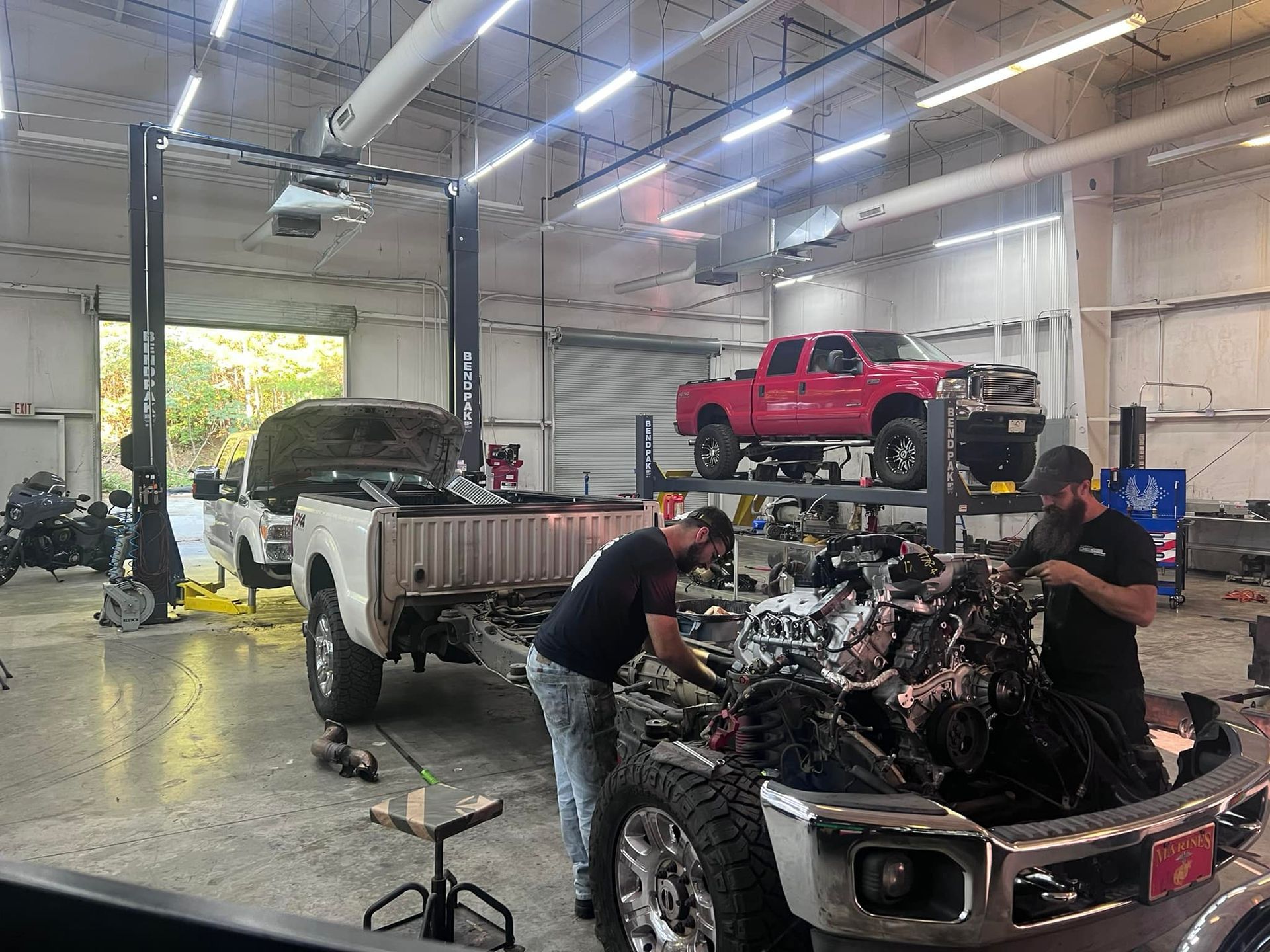 Two men are working on a truck engine in a garage.