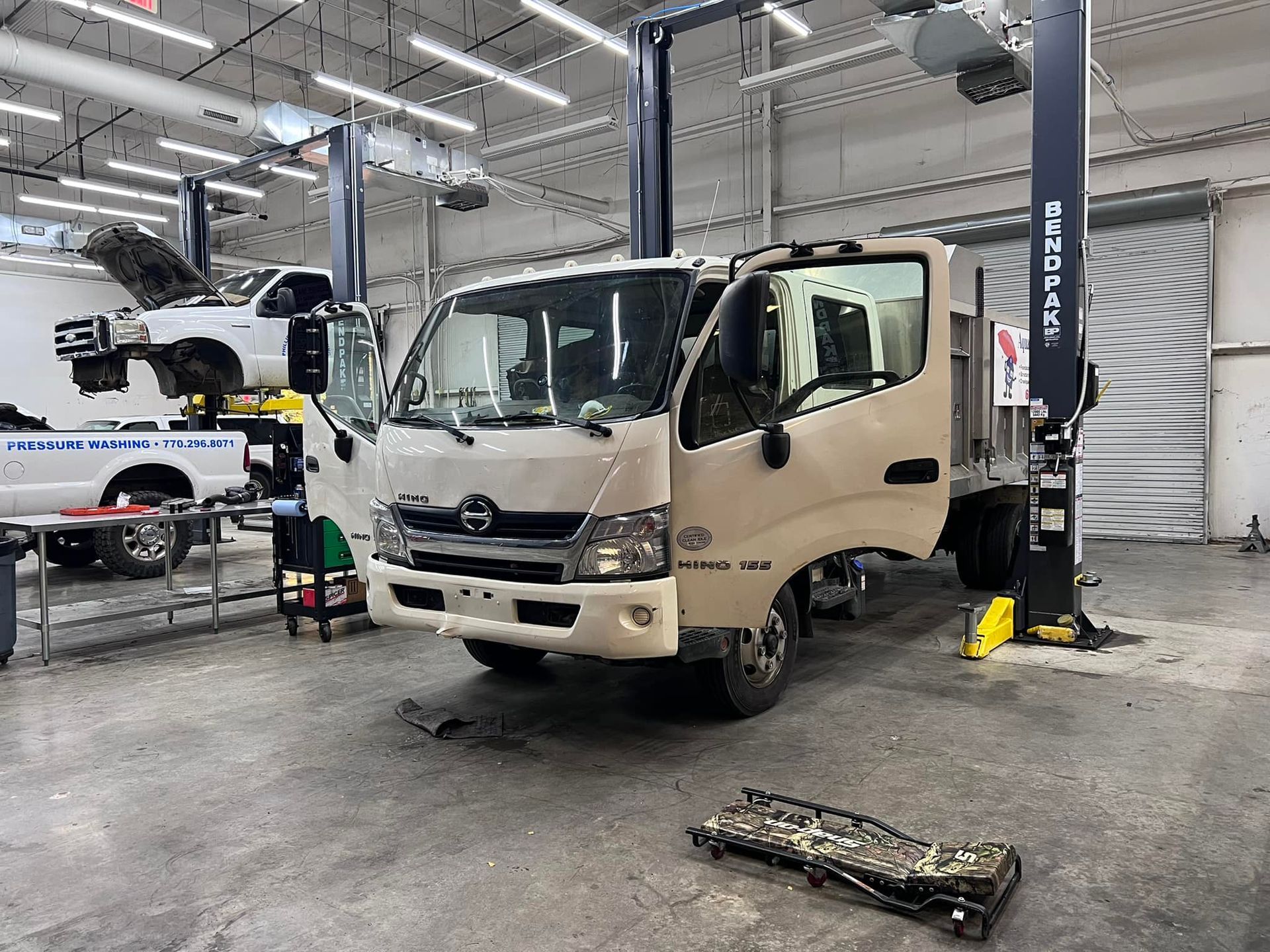 A truck is sitting on a lift in a garage.