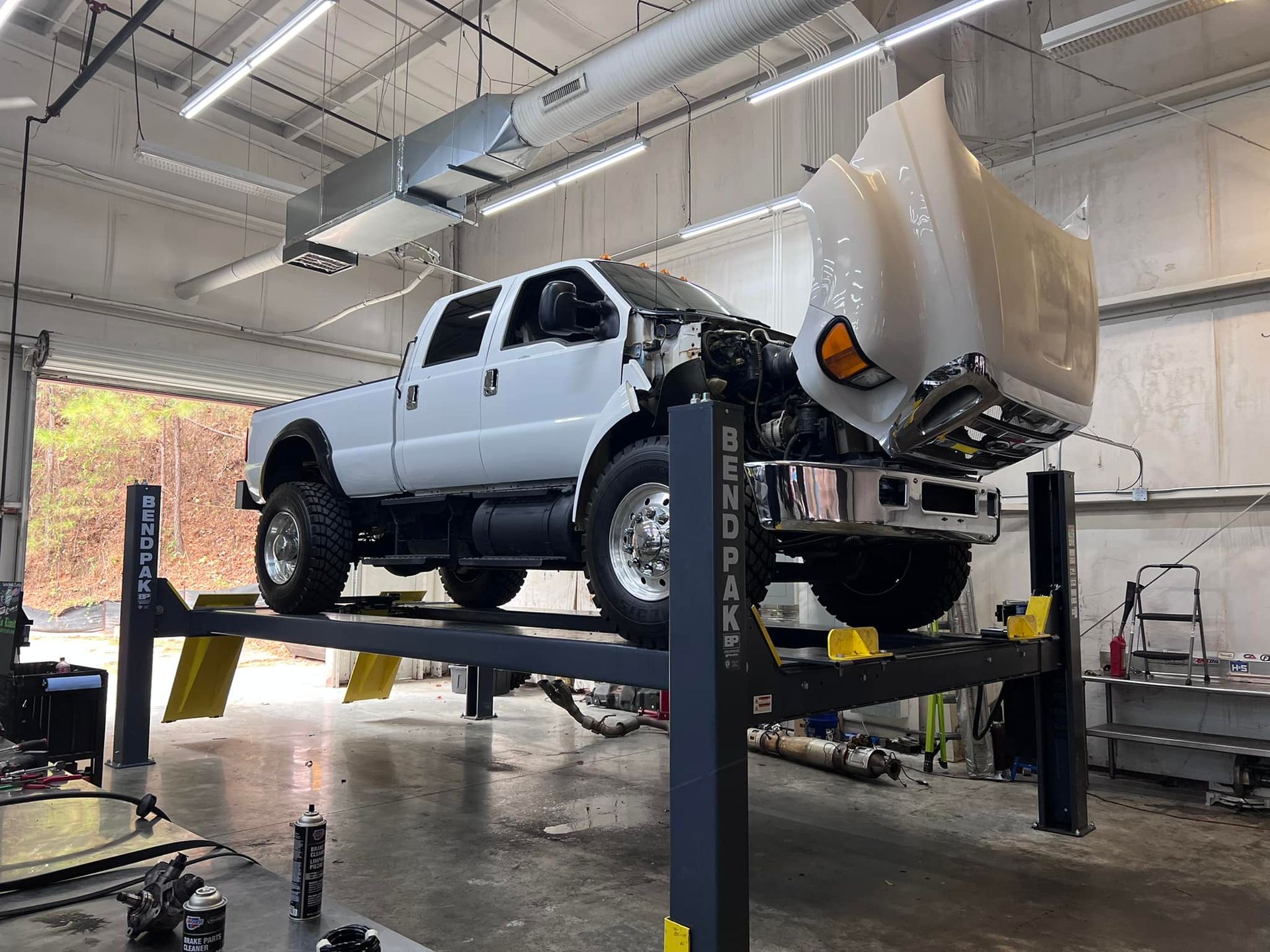 A white truck is sitting on a lift in a garage.