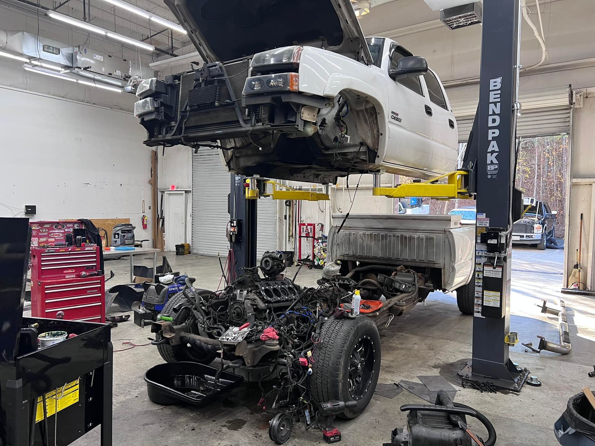A white truck is sitting on top of a lift in a garage.