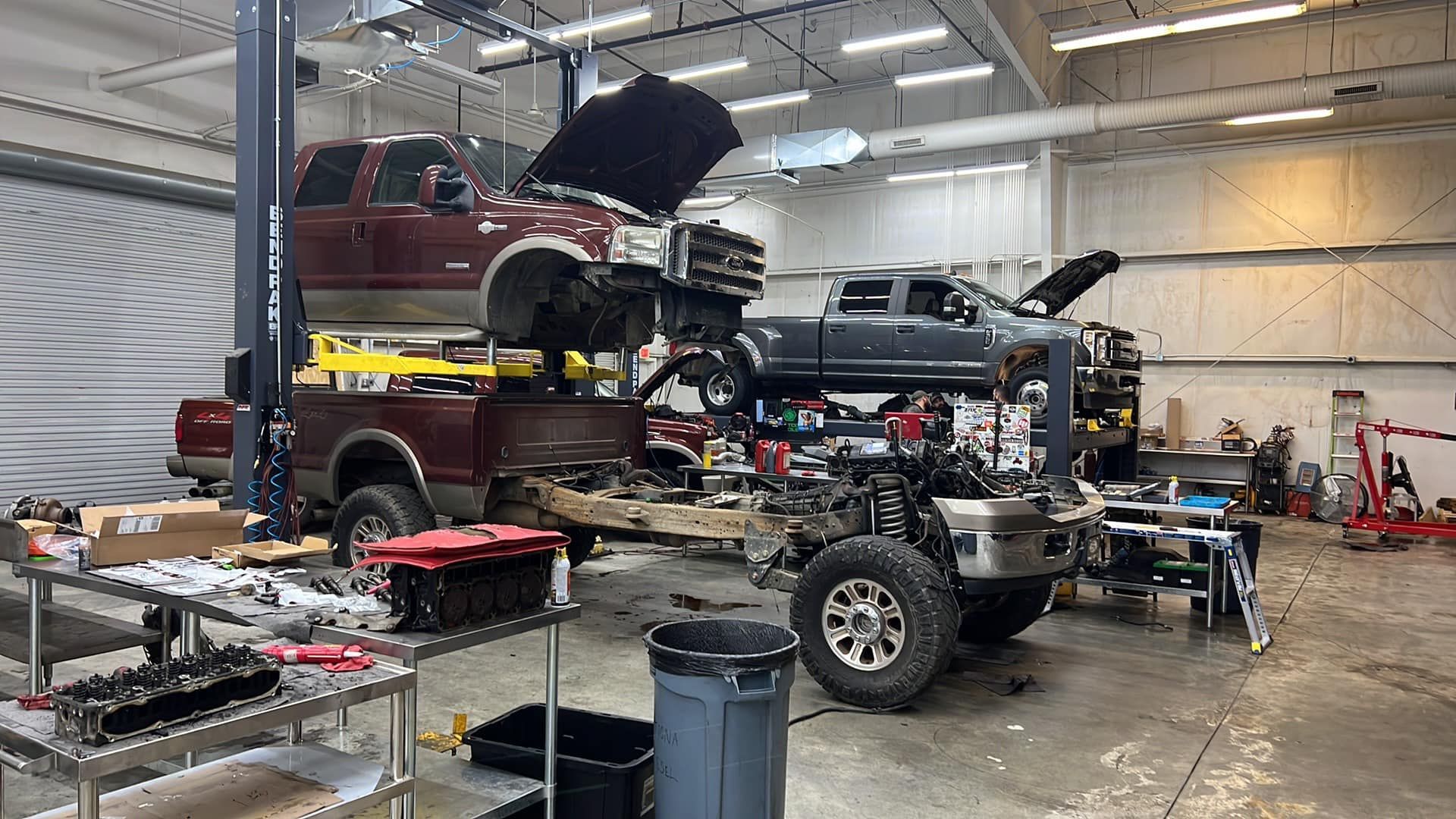 Two trucks are being worked on in a garage.