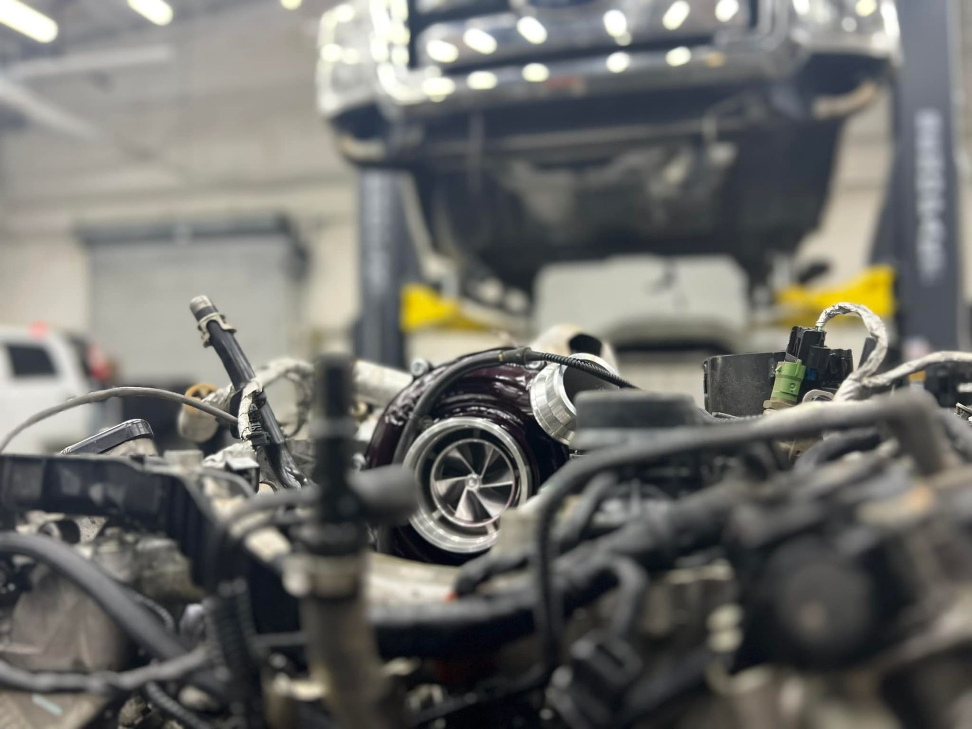 A car engine is sitting on a lift in a garage.