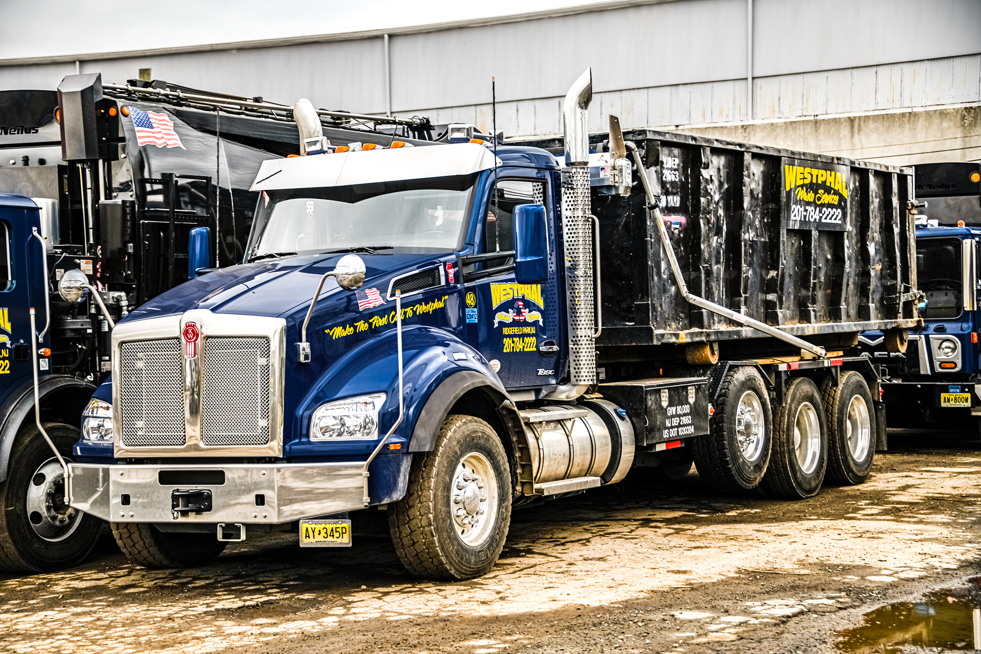 Blue dump truck with black cargo bed, parked outside.