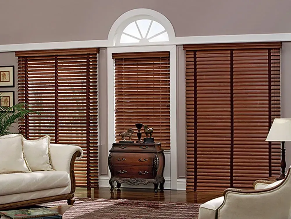 Living room with brown wooden blinds on three windows, furniture, and a rug.