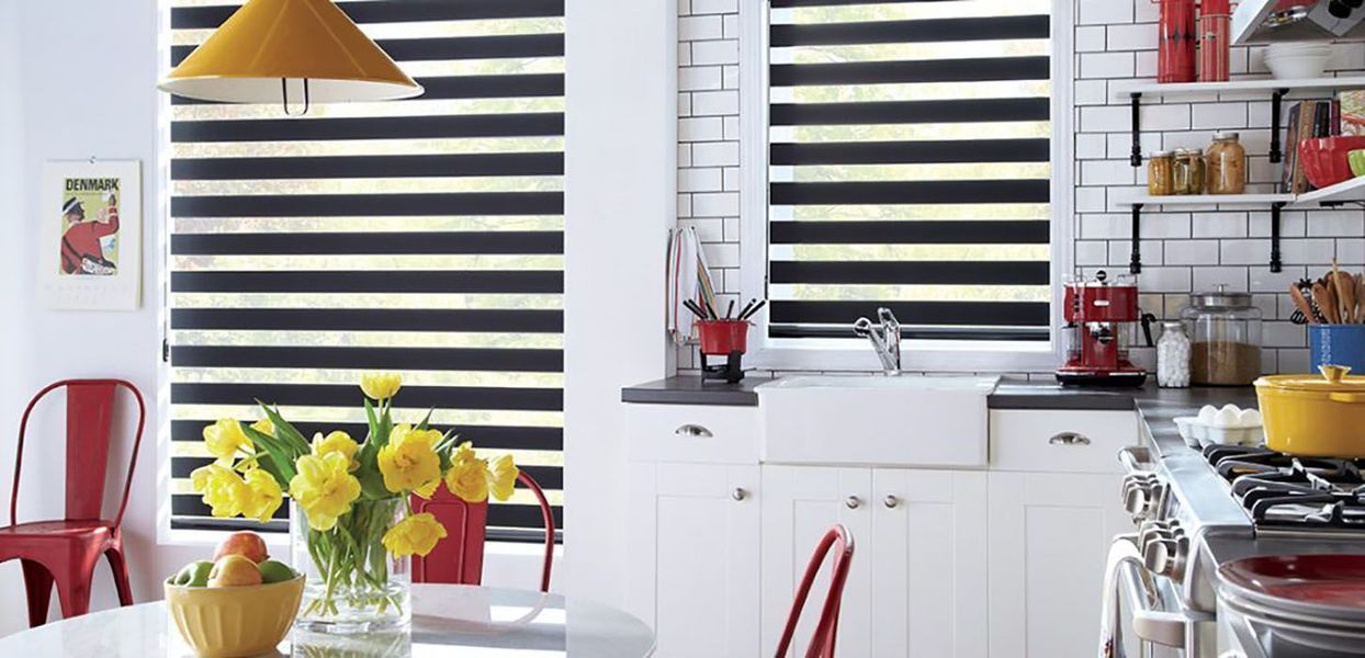 Bright kitchen with white cabinets, red accents, and yellow flowers. Black and white striped blinds cover the windows.