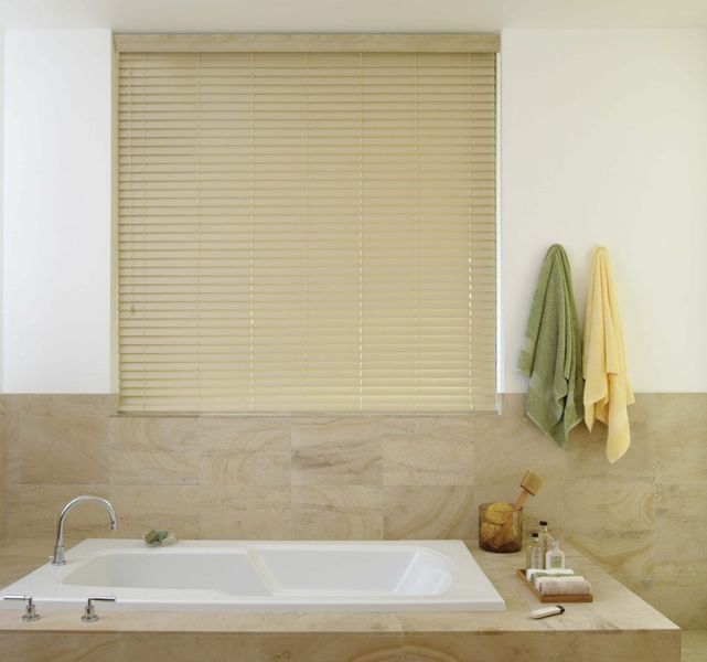 Bathroom with bathtub, closed beige blinds, and hanging towels.