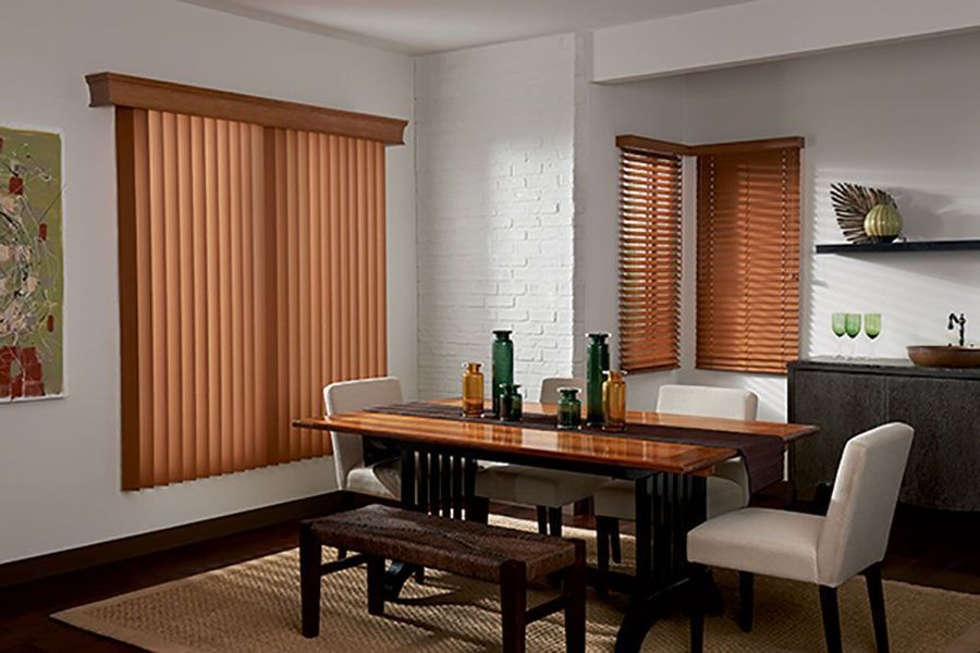 Dining room with wooden table and blinds; various colors of wood and tan; two windows.