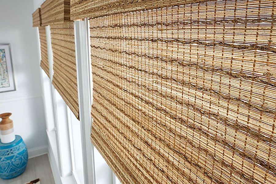 Woven bamboo shades over a window. Natural tan and brown tones with white window frame.