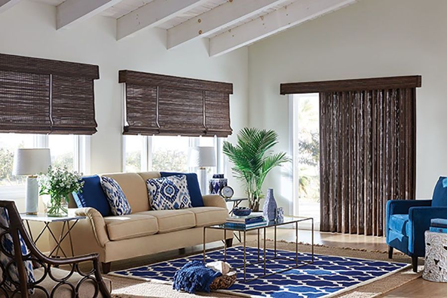 Living room with woven shades, tan sofa, blue accents, and a patterned rug.
