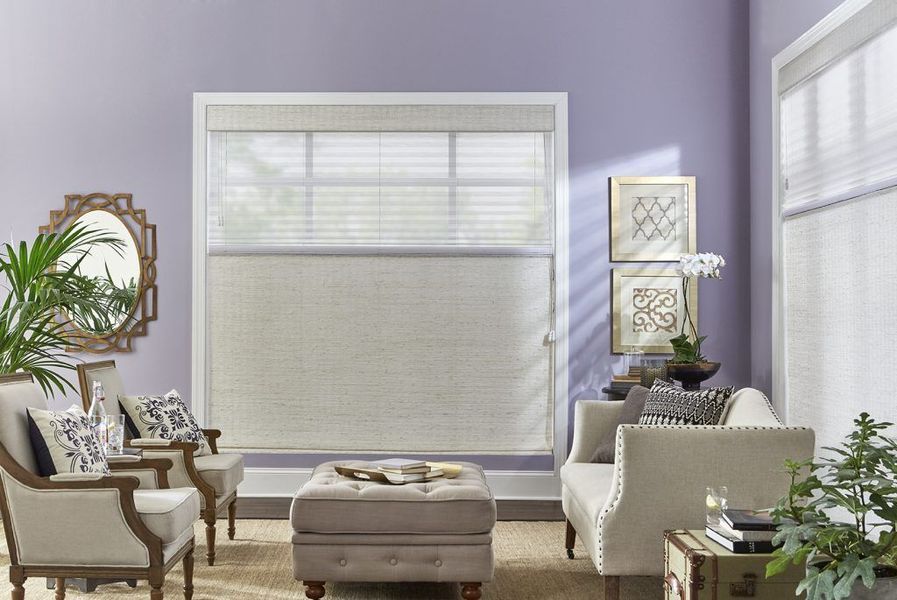 Living room with lavender walls, seating, and neutral blinds.