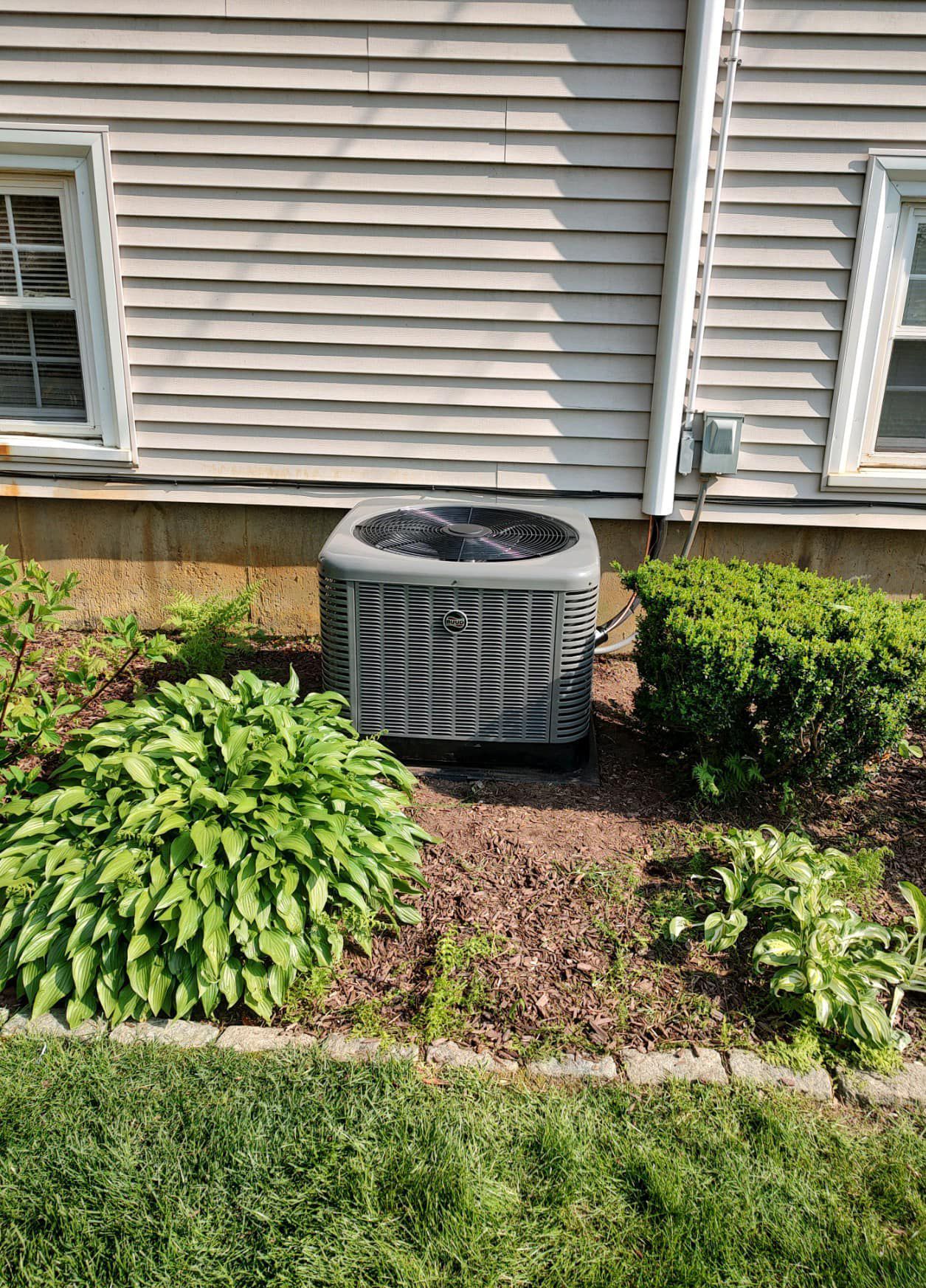 An air conditioner is sitting in the backyard of a house.