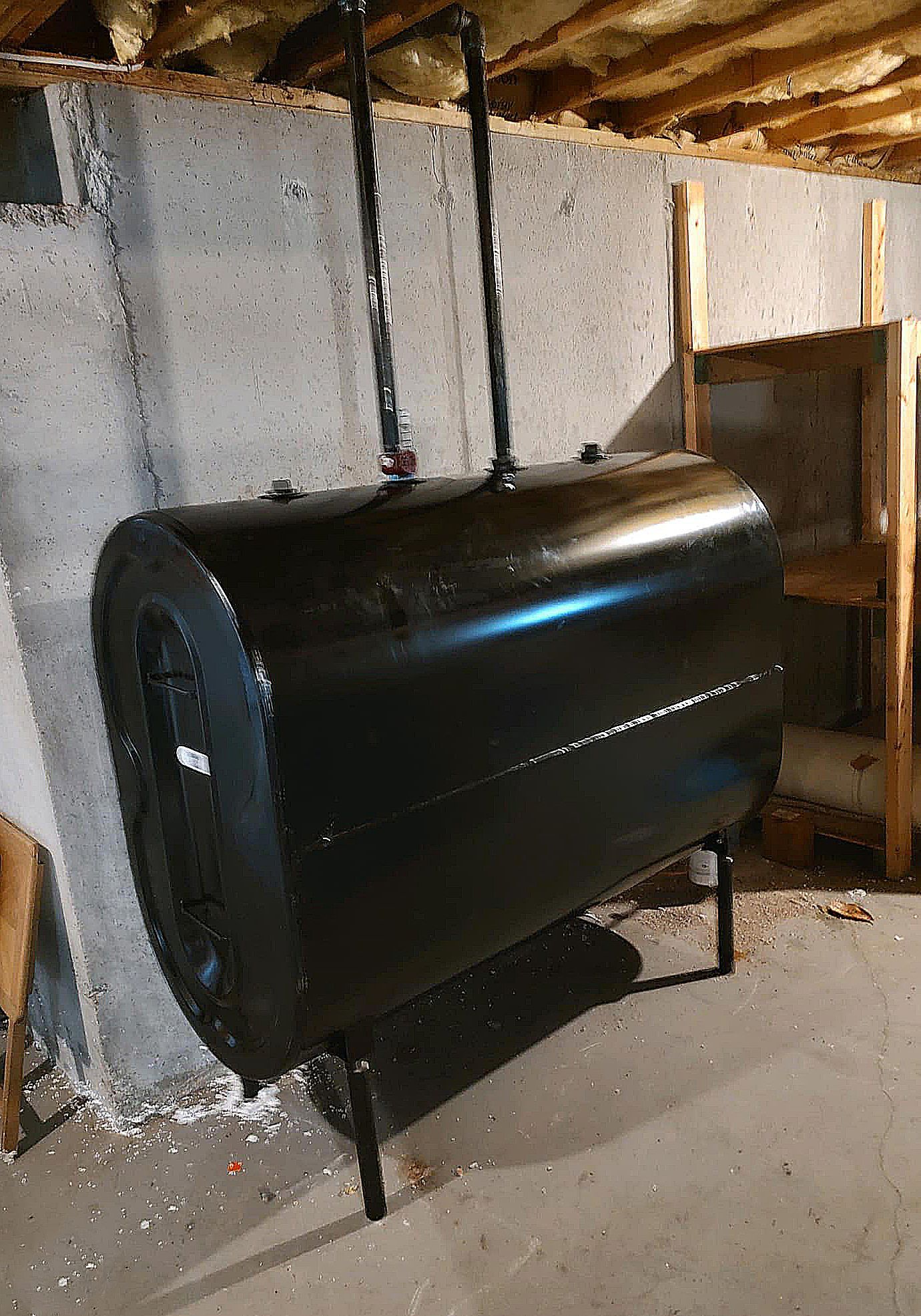 A large black tank is sitting in a basement next to a wall.